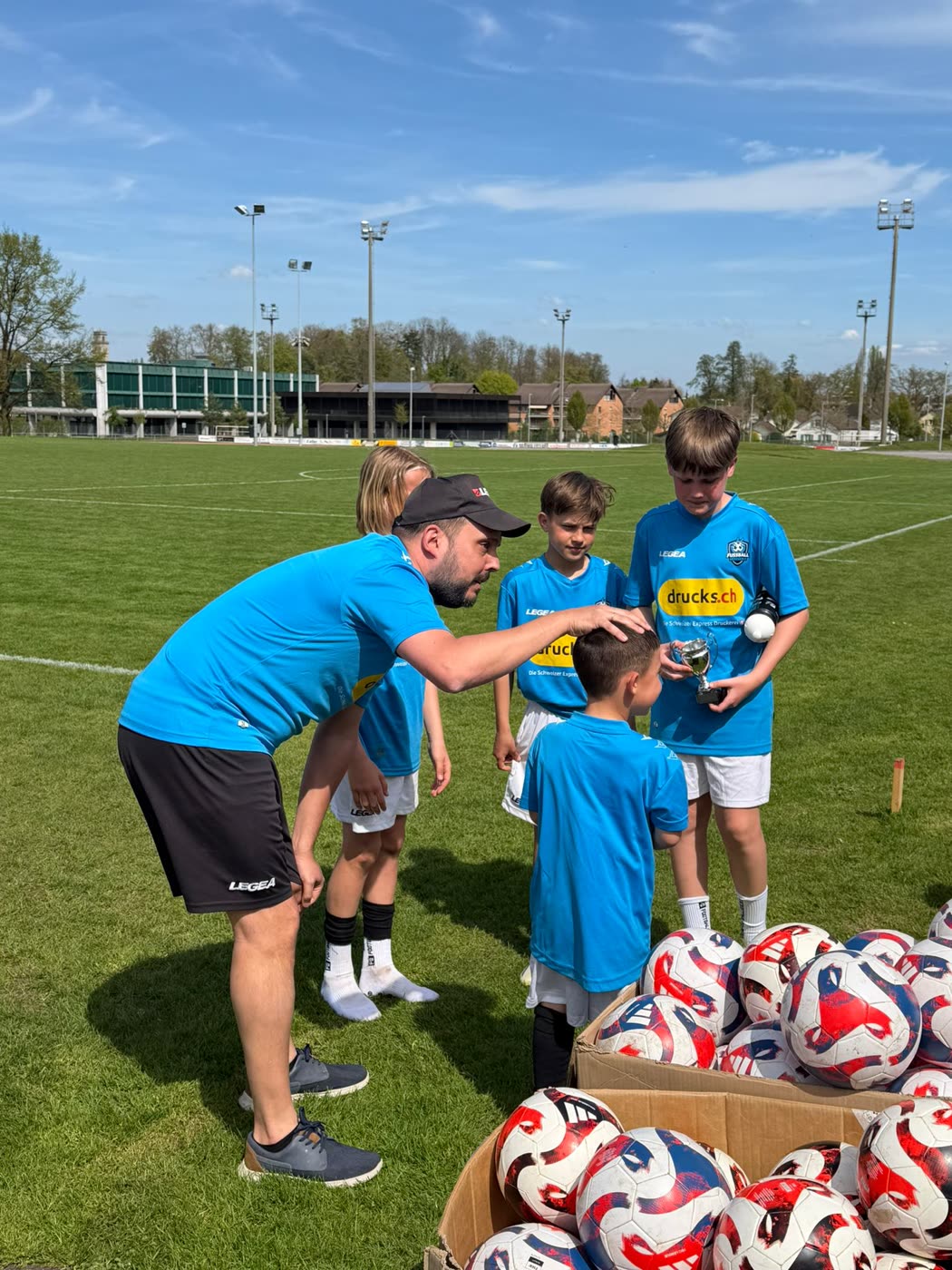 Coach mit Kindern im Camp, auf den Trikots das Logo des Partners drucks.ch